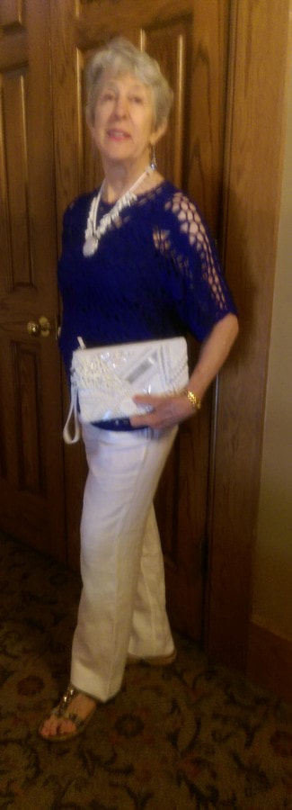 model wearing navy blue crocheted top and white pants